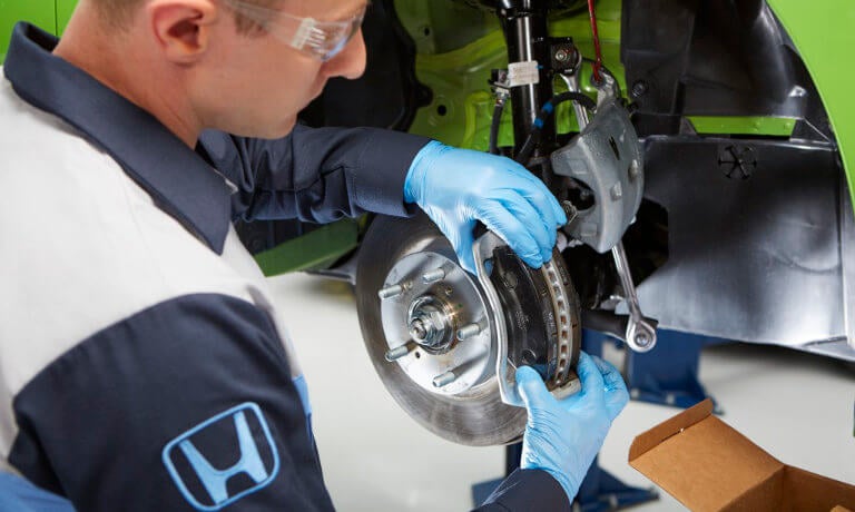 A Honda tech repairing car brakes